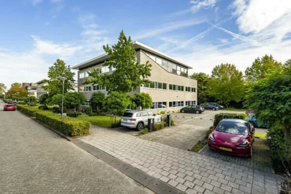 Kantoorpand aan de Jan Leentvaarlaan met omliggende parkeerplaatsen en groenvoorziening op een zonnige dag.
